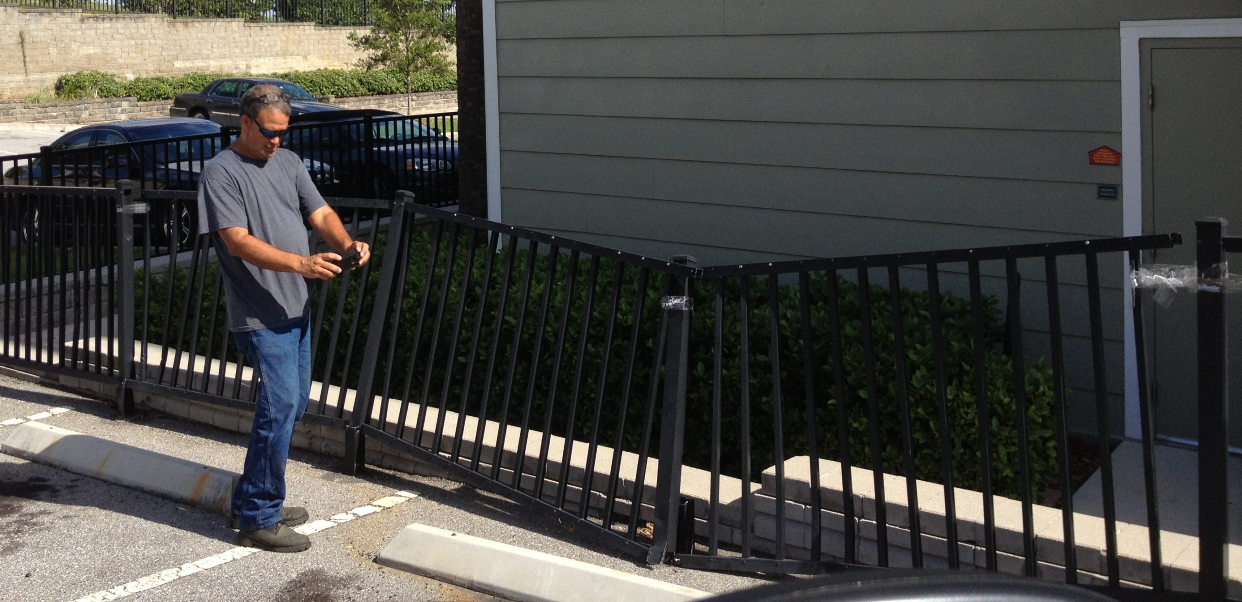 Bent commercial aluminum fence damaged by vehicle impact before emergency repair in Orlando, Florida.
